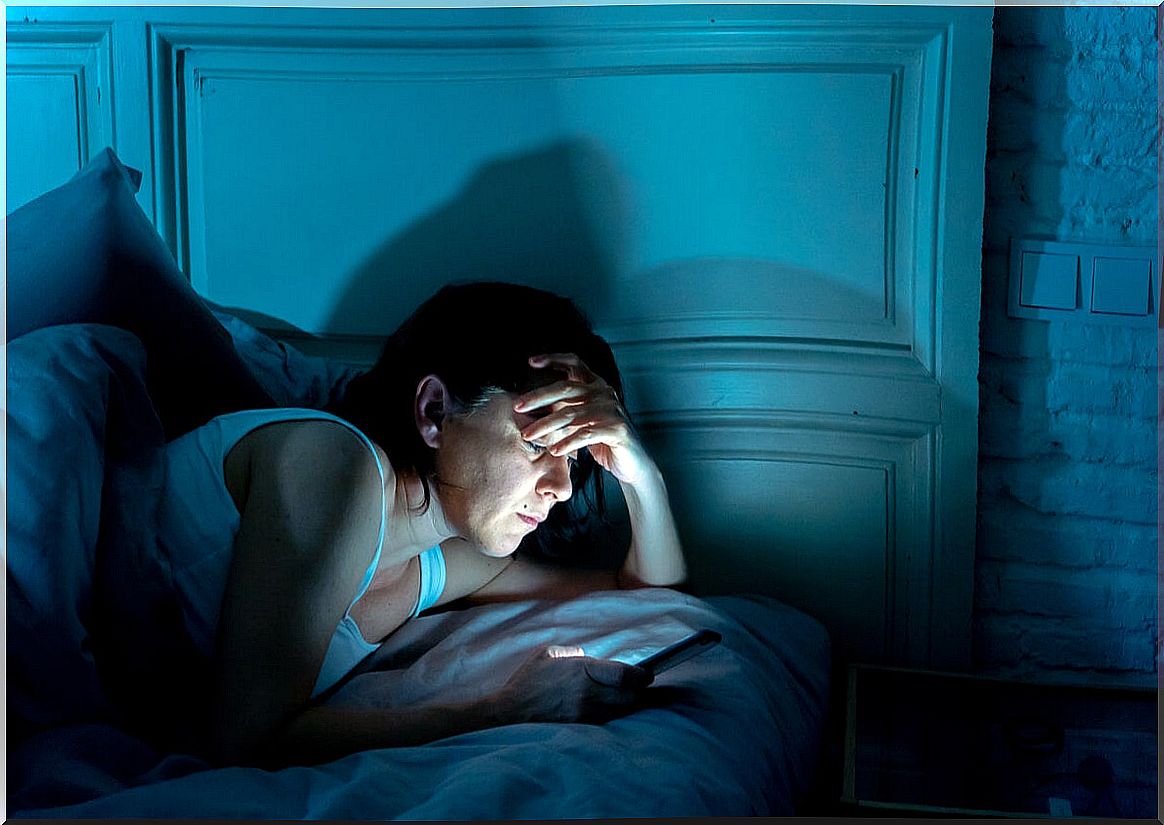 Woman reads cell phone at night in bed.