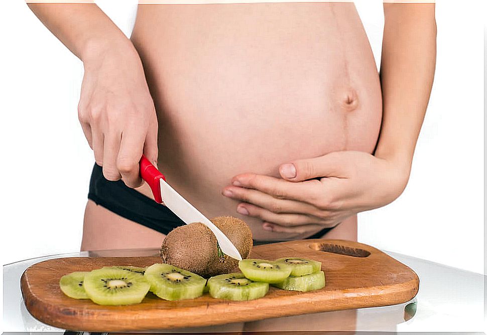 Pregnant woman splitting a kiwi.